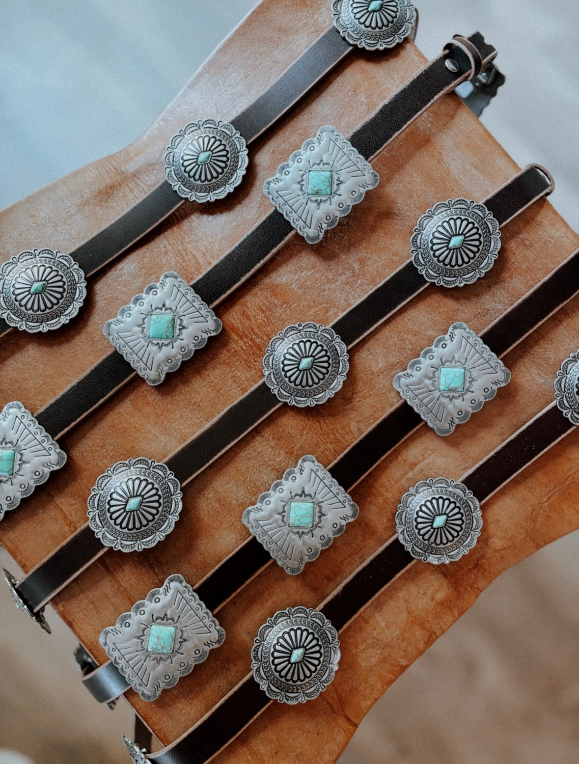 A leather concho belt set with turquoise stones