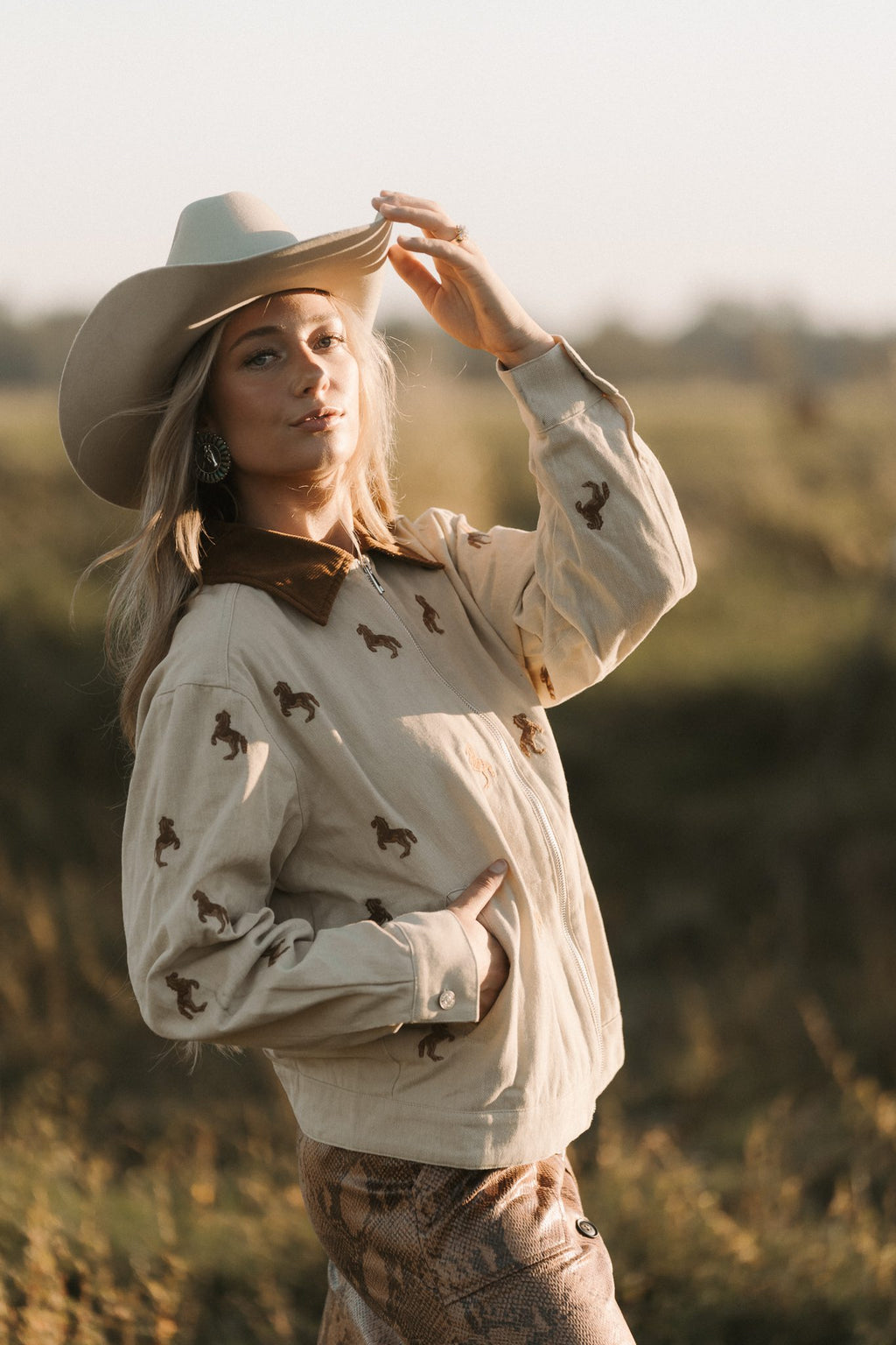 Woman wearing a cowboy hat and patterned shirt in a field