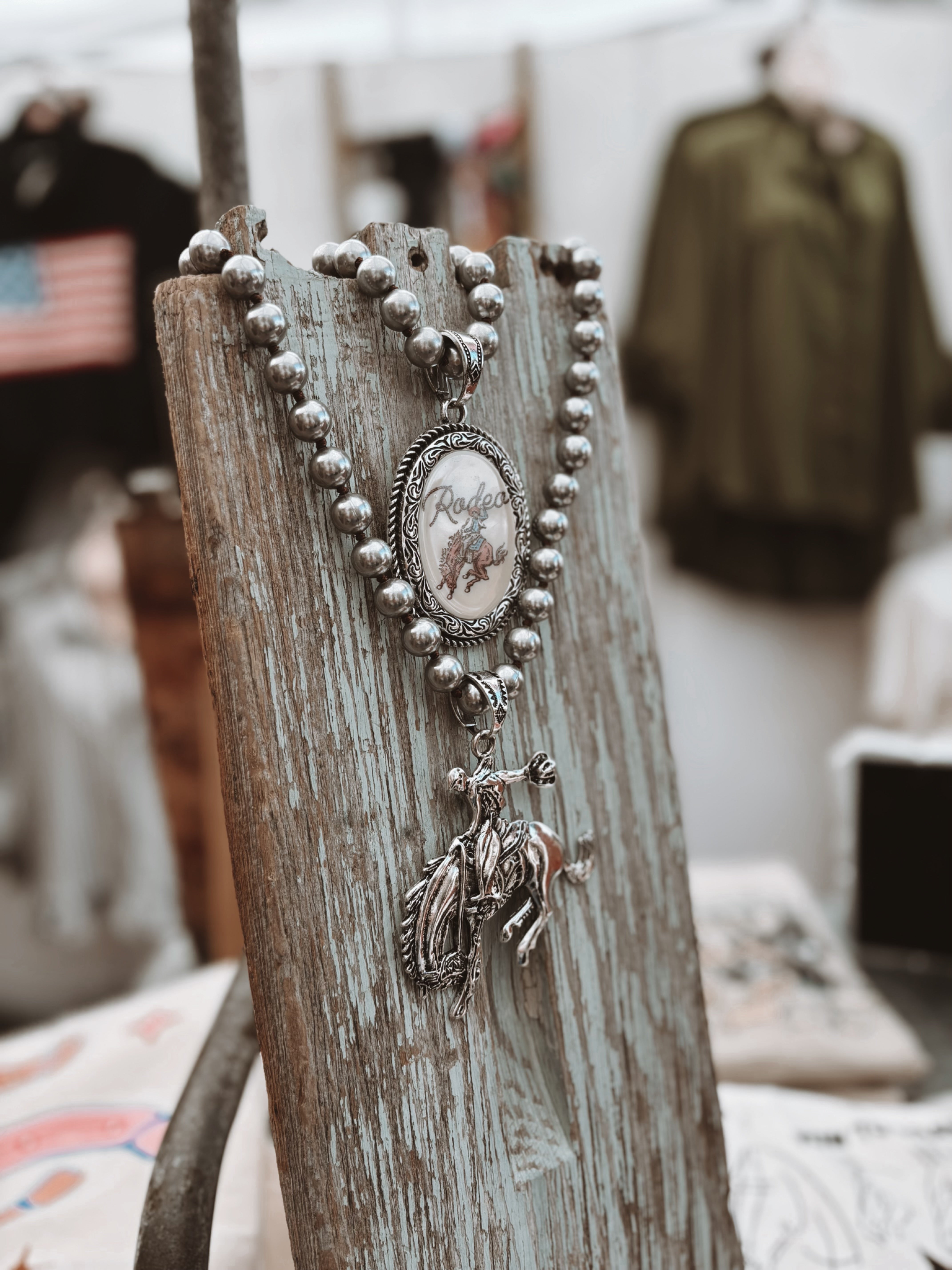 Silver necklace with a pendant on a rustic wooden stand