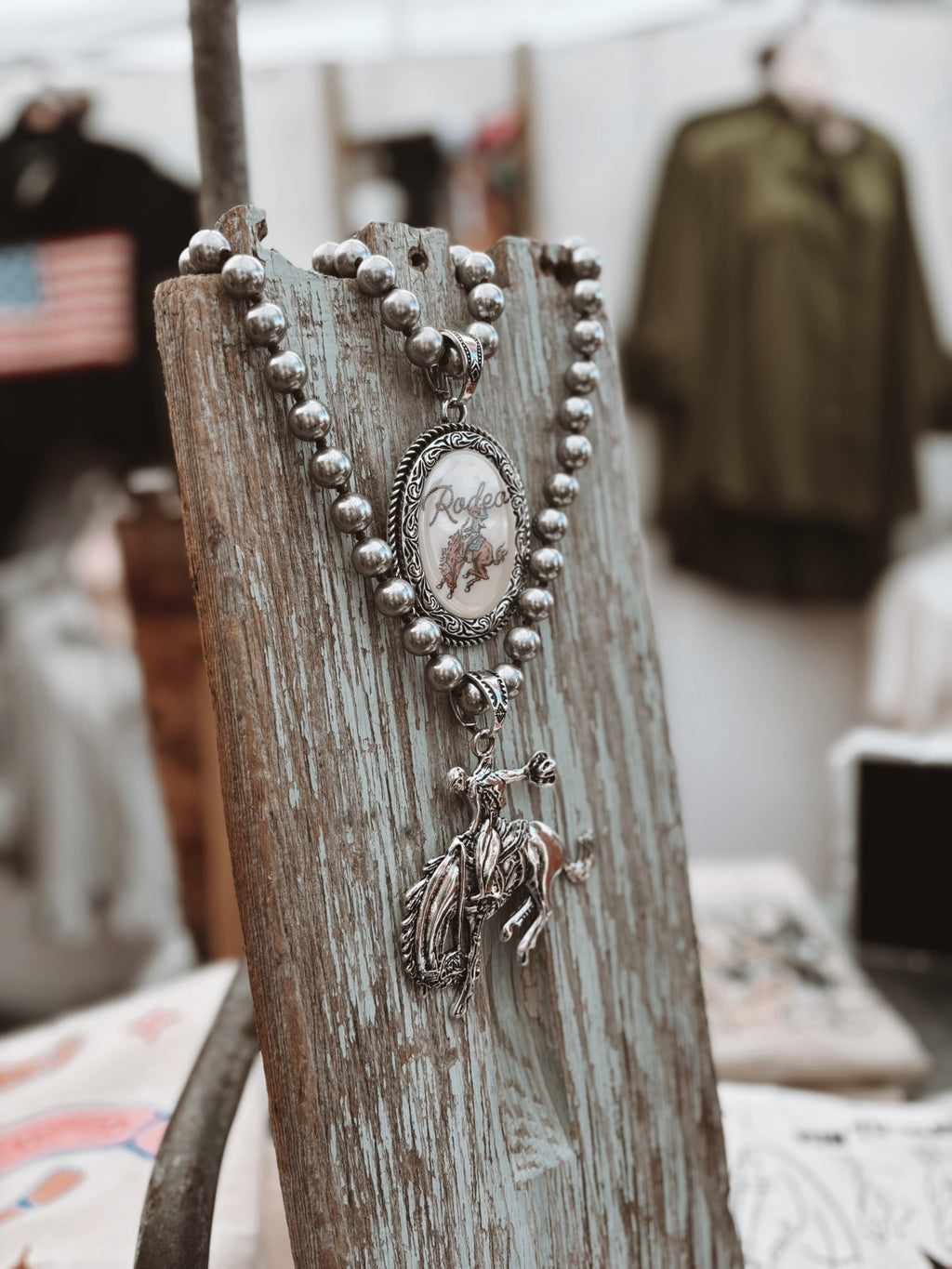 Silver necklace with a pendant on a rustic wooden stand