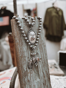 Silver necklace with a pendant on a rustic wooden stand