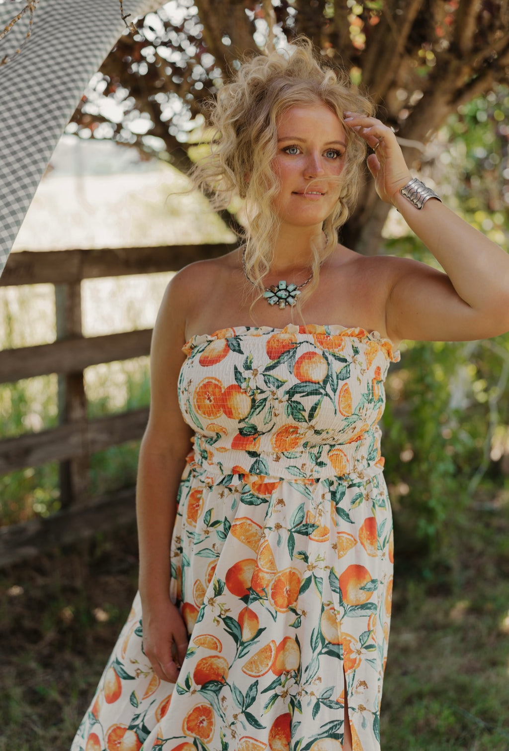 Woman wearing a floral dress with oranges in an outdoor setting