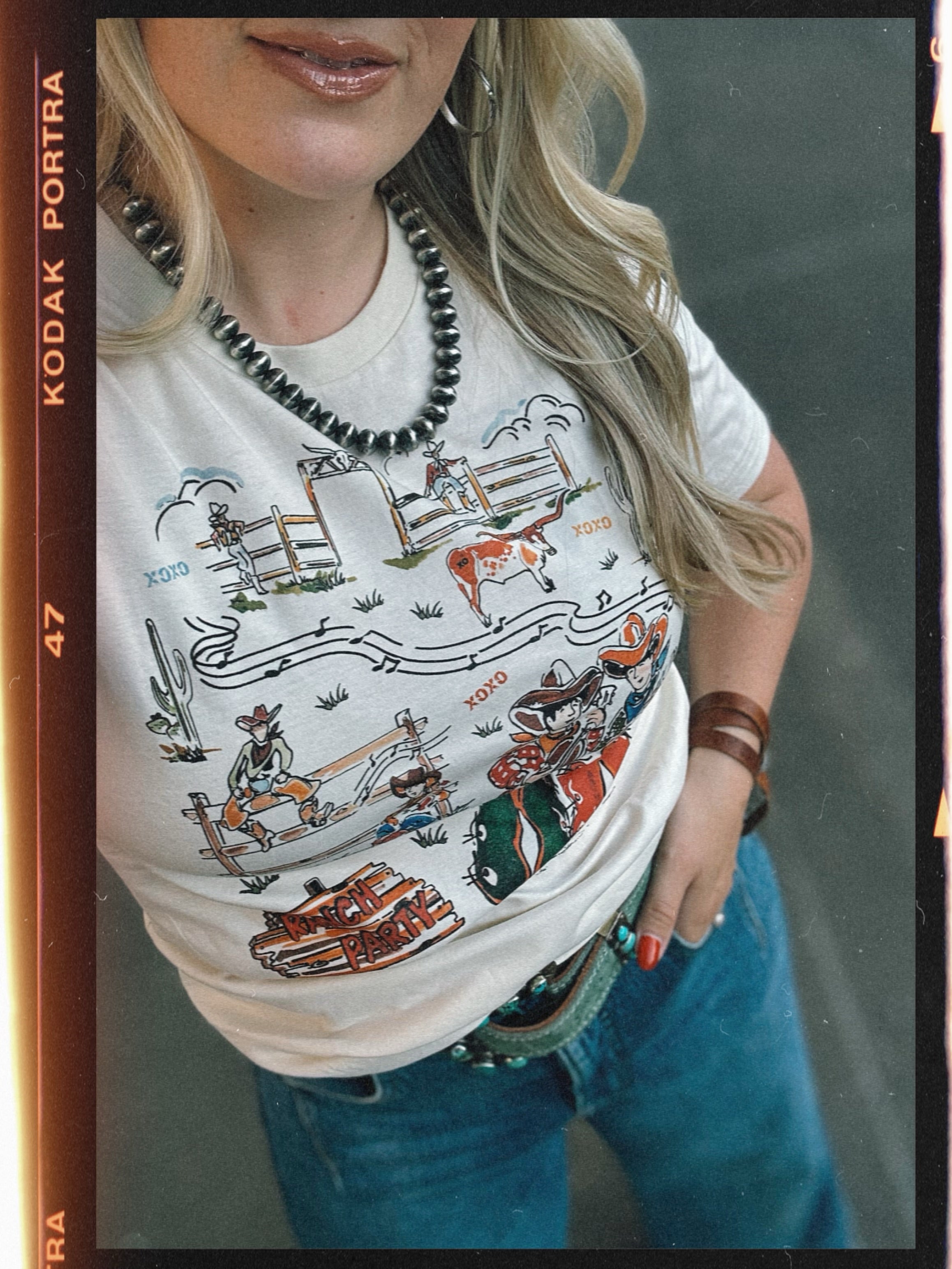 Person wearing a white t-shirt with a graphic design, standing against a neutral background.