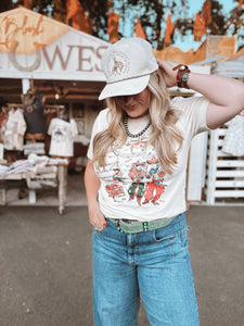 Woman wearing a graphic t-shirt and cap at an outdoor market.