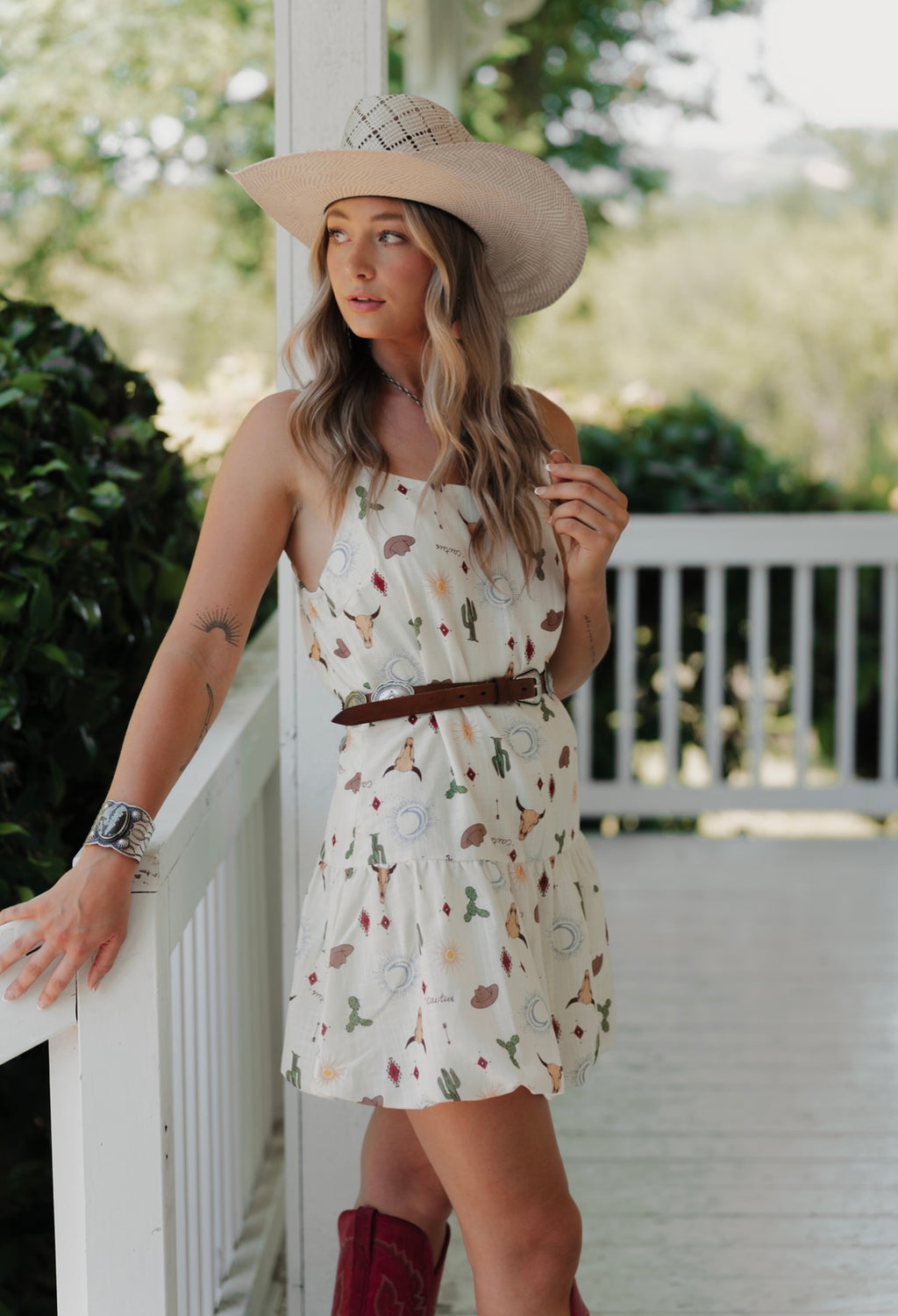 Woman wearing a Western patterned dress and wide-brimmed hat on a porch