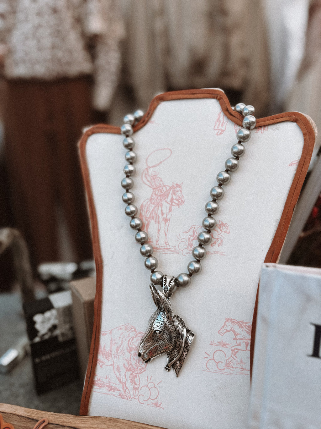 Necklace with horse pendant on a decorative stand with pink designs