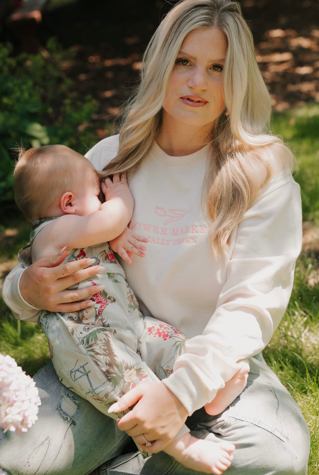 Woman holding a baby outdoors with greenery in the background
