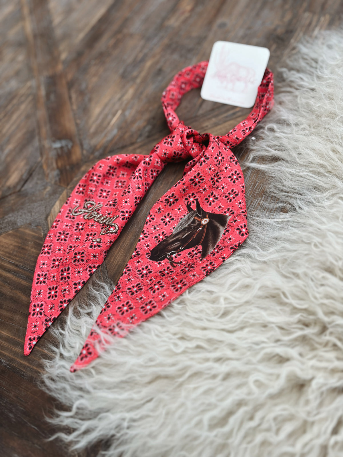 A red silk neck tie printed with black horses