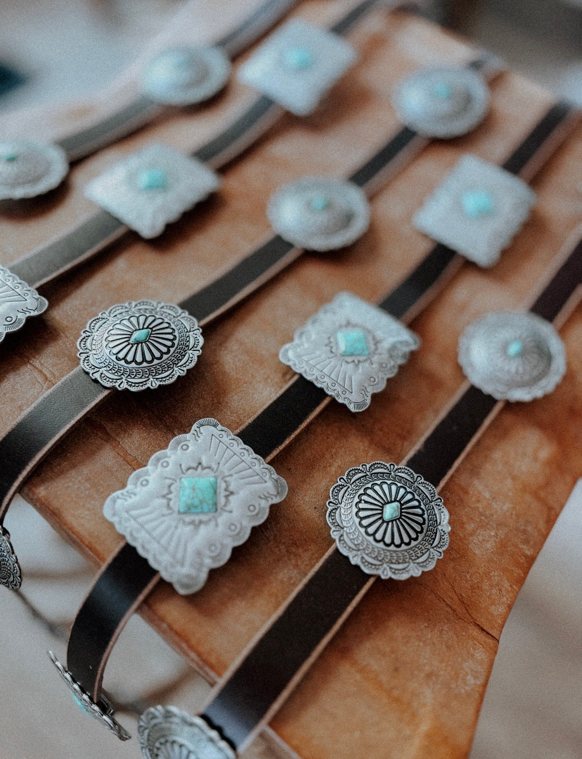 Brown leather belts set with engraved silver conchos and turquoise stones