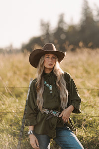 Woman in a cowboy hat and green shirt standing in a field