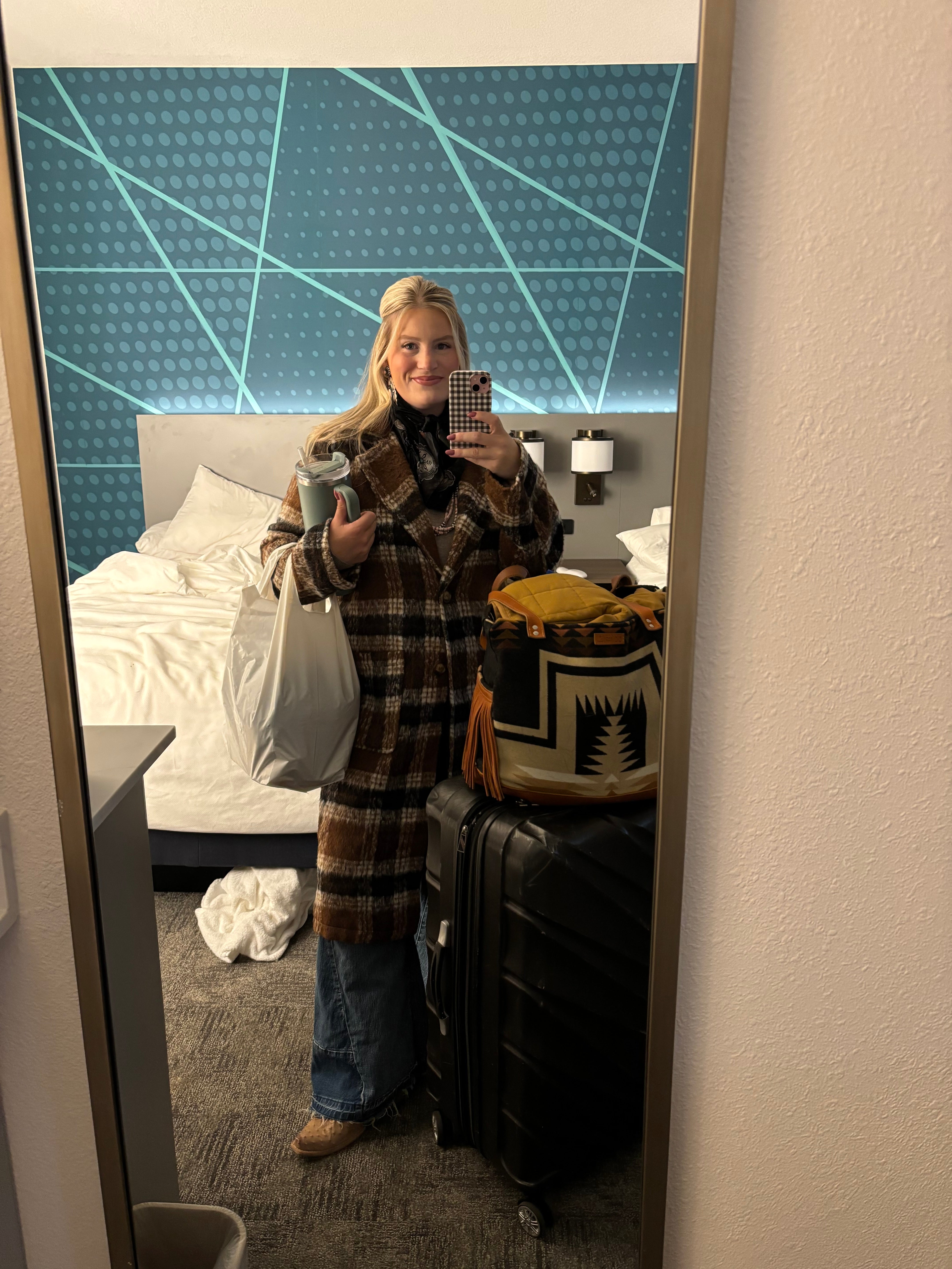 Person standing in front of a mirror with a guitar and plaid jacket.