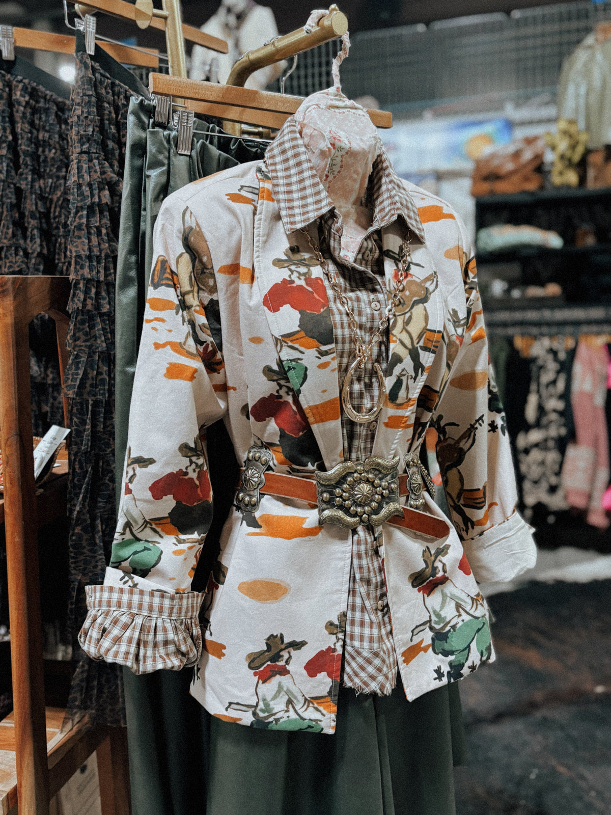 A retro cowboy print blazer photographed flat on a pale background