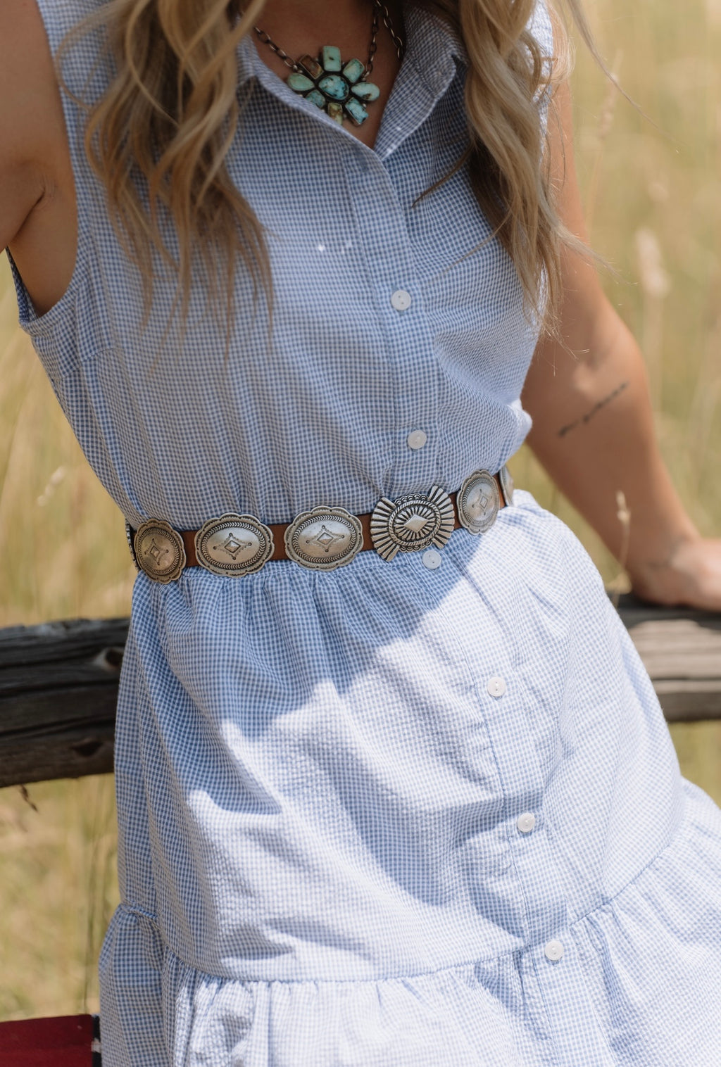 Woman wearing a light blue dress with a decorative belt in a natural setting