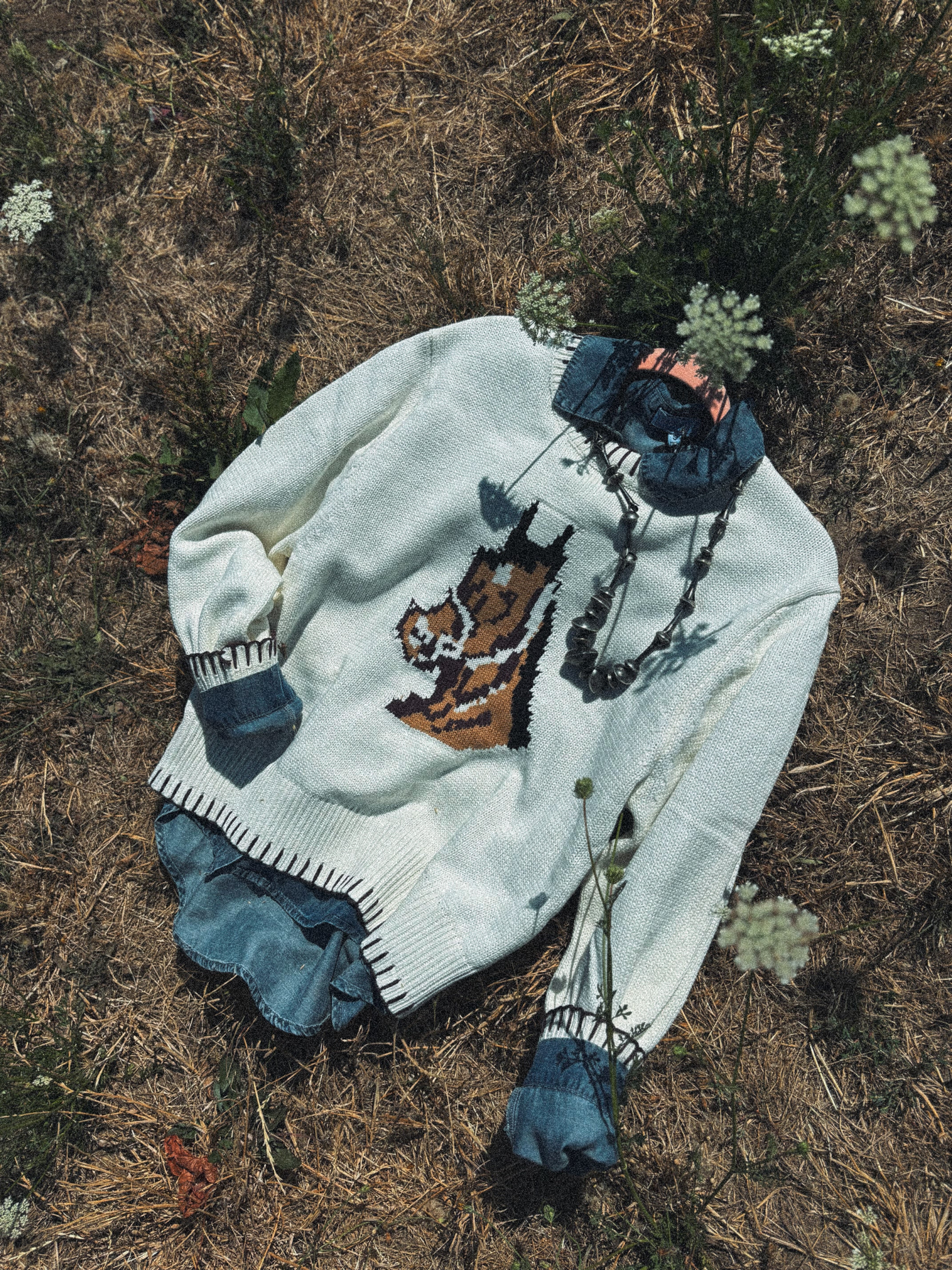 White sweater with embroidered  horse design on a natural background