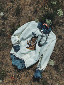 White sweater with embroidered  horse design on a natural background